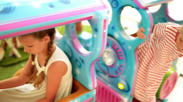 Two beautiful little girls ride small train toy