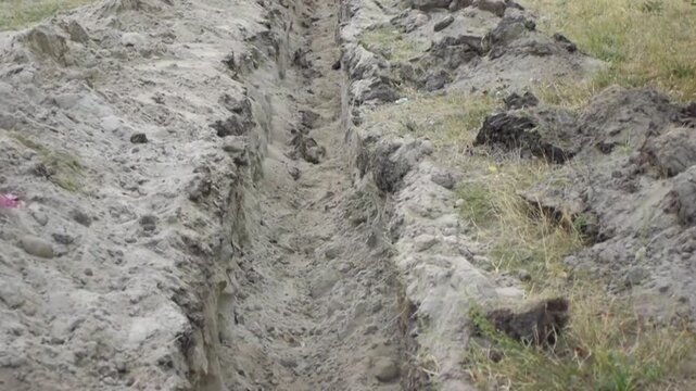 Two little girls jump over an earthen ditch
