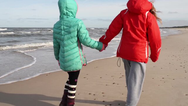 Two sisters walking along shore of Baltic Sea