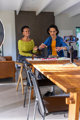 Obraz premium Diverse female friends filming craft demo with small bottles at home with smartphone and ring light