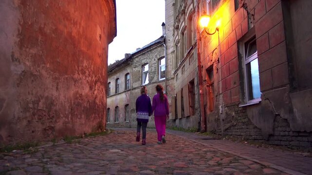 Two little beautiful girls walk on Dvasios Street in Vilnius city, capital of Lithuania.