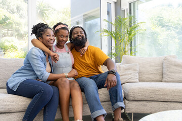 Obraz premium African American family sitting on light sofa in modern living room with palm and wristwatch