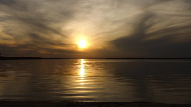 Two little sisters happily playing and having fun in front of the setting sun and the big lake. Beautiful sunset.