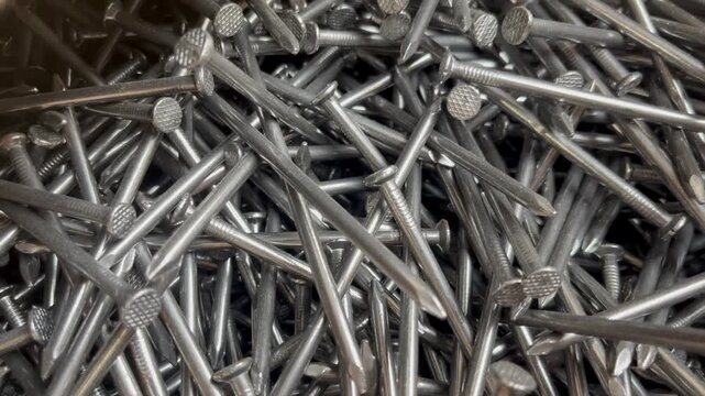 A messy heap of shiny steel wire nails for woodworking. Macrophotography of industrial fasteners and metal hardware equipment 
