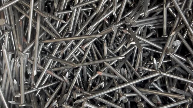 A messy heap of shiny steel wire nails for woodworking. Macrophotography of industrial fasteners and metal hardware equipment 