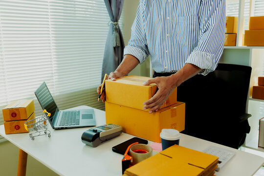 Professional young businessman double-checking shipping labels and customer addresses on parcel boxes for zero-error delivery.