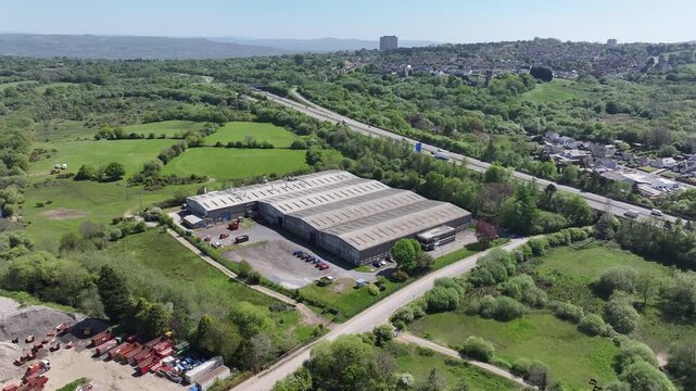Aerial drone view of industrial factory foreground with M4 motorway and Swansea countryside background, Wales, UK.
