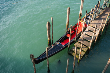 Venetian gondola moored on the wooden pier on Grand canal in Venice, Italy. © smallredgirl