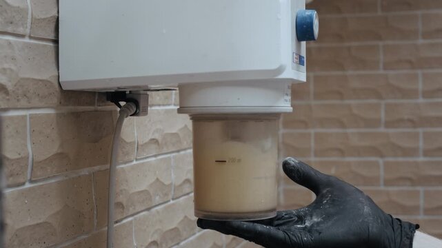 Dental lab worker wearing gloves mixing plaster for impressions using a specialized vacuum mixer