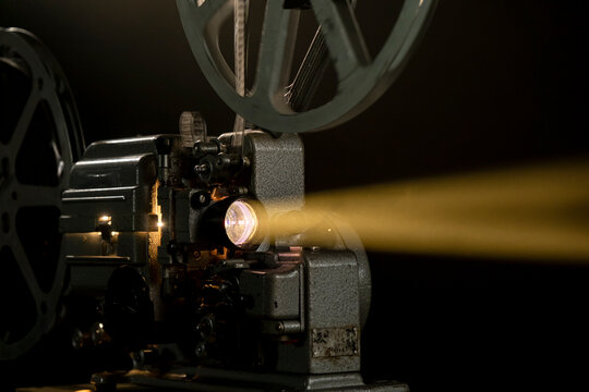 Old film projector shows light beam in dark room during movie screening