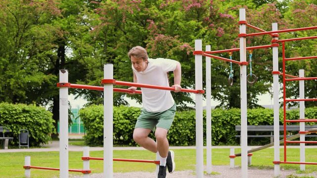 4K video of a young man doing a fitness workout, performing dips on parallel bars at an outdoor calisthenics gym park. High quality footage