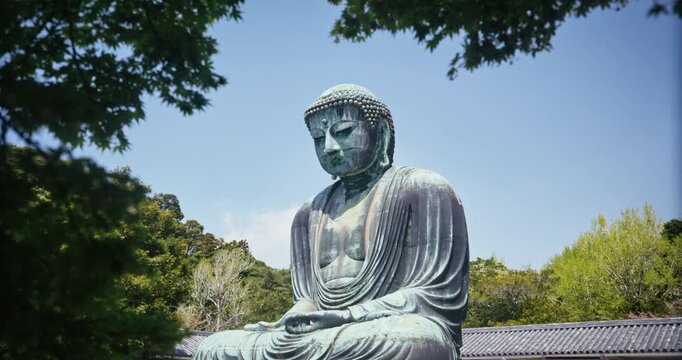 Ancient, Bronze Buddha Statue Seen Through Tree Canopy With Clear Sky In Japan - Steady Cam Forward