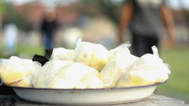 boiled cassava in plastic with blur of people walking