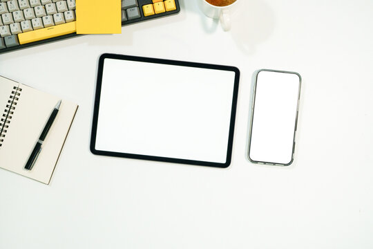 Top view flat lay of tablet and smartphone with blank white screens on a clean workspace, perfect for app UI mockup and digital product presentations.