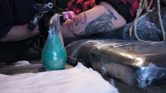 Tattoo artist working on design in studio with various tools and ink during daytime session