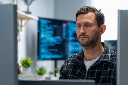 Male programmer and data science specialist debug algorithms type Python and SQL on laptop and monitor in a hybrid workspace focusing on analytics automation and software development.