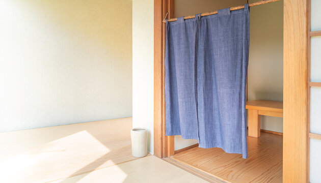 藍色の暖簾が掛かった静かな和室の入口と余白のある空間