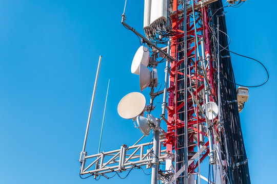 Cellular tower equipment with microwave antennas and communication hardware on telecom mast
