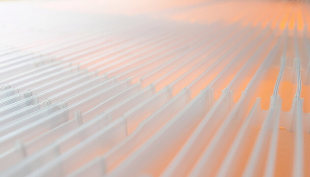 Abstract industrial texture close up of translucent white fluted polycarbonate sheet with soft diffused warm orange backlight