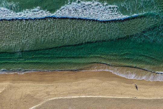 Aerial scene capturing One Mile Beach near Forster, NSW, Australia, from directly above. The downward perspective highlights golden sand meeting clear turquoise water and the whitewash of the waves
