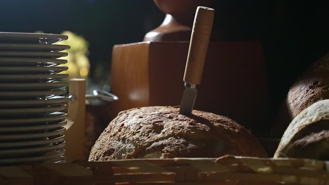 A loaf of sourdough bread on a table with a knife stuck in it at a fancy party
