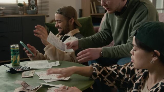 Multiethnic young adults reviewing past due bills, arguing and discussing financial problems with stressed and worried expressions. Student loan services, budgeting apps, or banking commercials