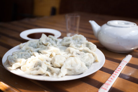 Traditional Chinese dumplings served with soy sauce and chopsticks on a wooden table, China