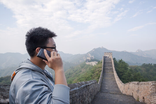 Young chinese man calling on mobile phone on the Great Wall, Jinshanling, Hebei, China