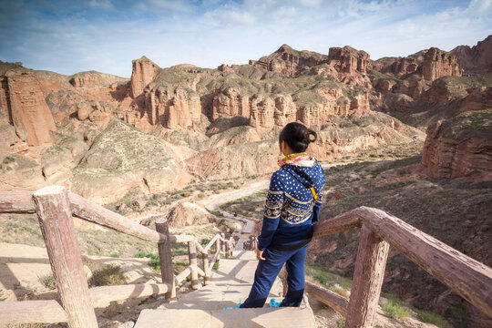 Young tourist admiring the colorful rock formations of the Danxia landform, Zhangye, Gansu, China