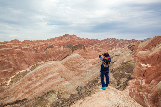 Woman exploring the vibrant and colorful rock formations of the Danxia landform, Zhangye, Gansu, China