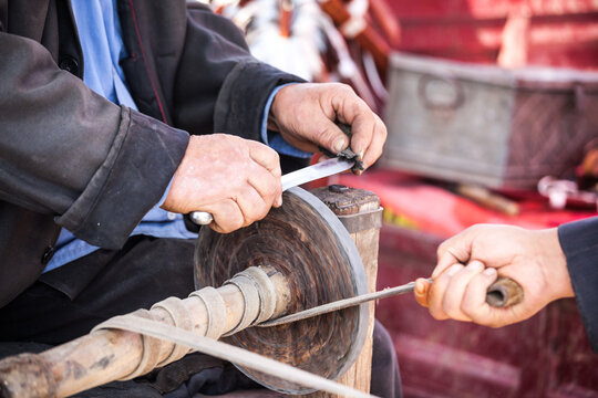 Man sharping a knife at Kashgar sunday livestock market, Kashgar, Xinjiang, China