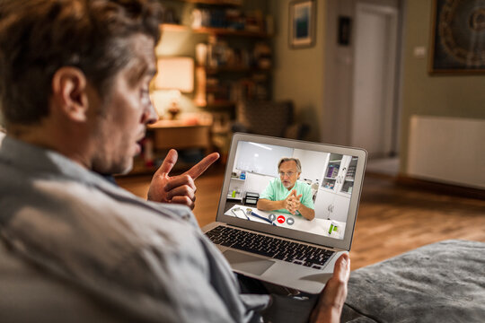Man consulting doctor via video call at home
