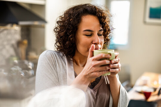 Woman sipping hot coffee in a home kitchen
