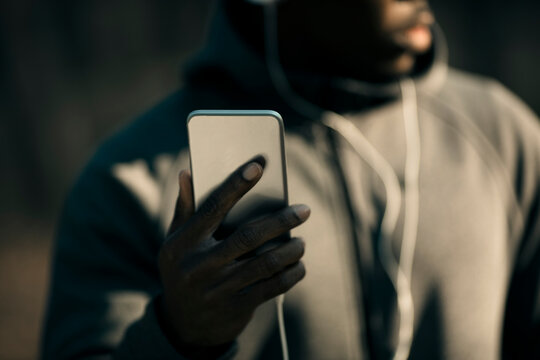 Close-up of athlete checking smartphone while listening outdoors