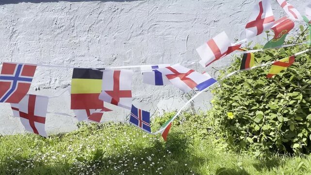 A vibrant display of international flags and decorative bunting fluttering in the breeze. Representing countries from around the world, this colourful scene celebrates unity, culture, diversity, and g