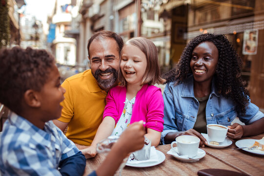 Happy family with kids enjoying coffee at outdoor cafe