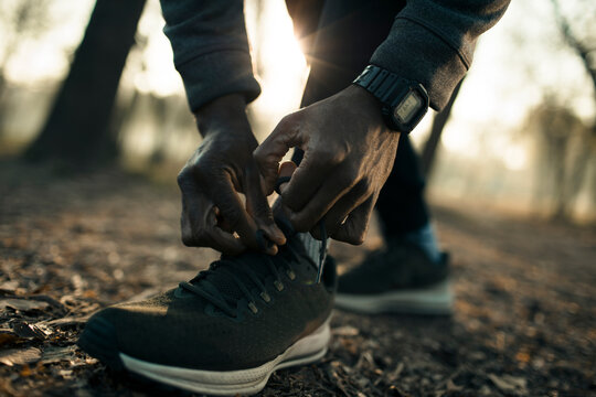 Runner tying shoelaces on forest trail at sunrise