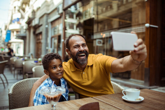 Father and son taking selfie at outdoor cafe