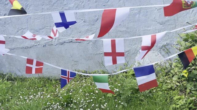 A vibrant display of international flags and decorative bunting fluttering in the breeze. Representing countries from around the world, this colourful scene celebrates unity, culture, diversity, and g