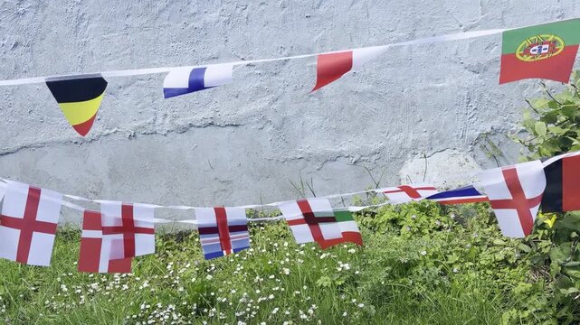 A vibrant display of international flags and decorative bunting fluttering in the breeze. Representing countries from around the world, this colourful scene celebrates unity, culture, diversity, and g