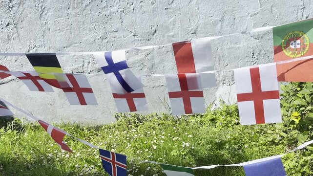A vibrant display of international flags and decorative bunting fluttering in the breeze. Representing countries from around the world, this colourful scene celebrates unity, culture, diversity, and g