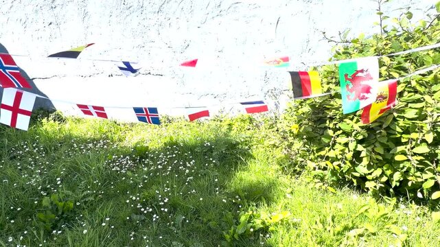 A vibrant display of international flags and decorative bunting fluttering in the breeze. Representing countries from around the world, this colourful scene celebrates unity, culture, diversity, and g