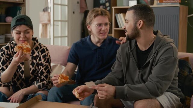 Diverse young adult students, including Asian woman, Caucasian and African American man, eating pizza while calculating expenses on receipt. Ideal for student budgeting or youth lifestyle ads
