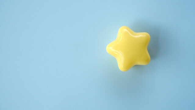 A single yellow star-shaped object isolated on a light blue background, symbolizing achievement or a top rating.