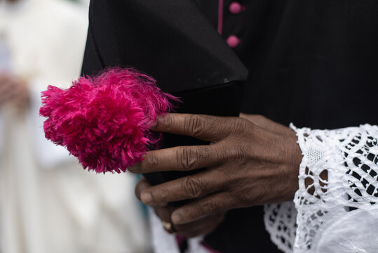 Clergyman holding a biretta with a pink pompom