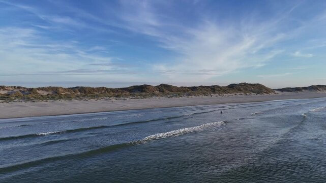 Golden hour approach over dunes toward beach
