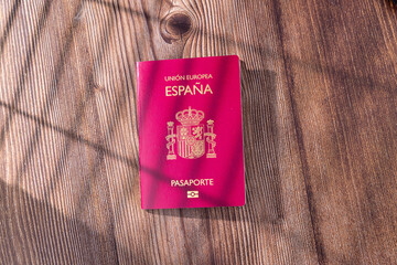 Top view of a red Spain passport with the official golden coat of arms isolated on a neutral background surface for travel themes © Shutterly