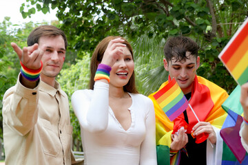 Obraz premium Gathering gay men transgender women and lesbians carrying rainbow flags celebrate the pride and joy LGBTQ community and their gender identities marching parade demand equal rights.