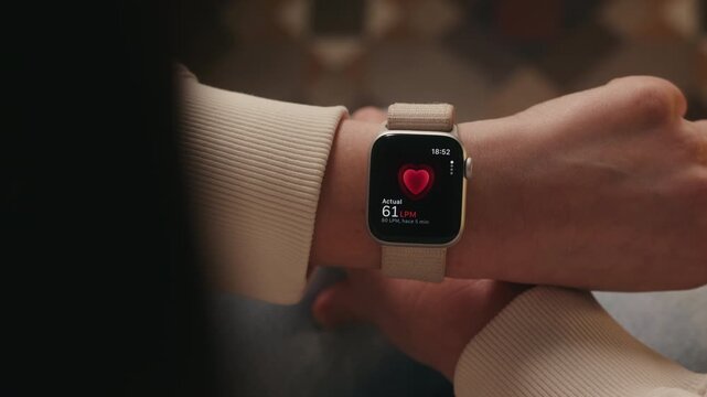 Over-the-shoulder view of a person checking heart rate on a smartwatch worn on the wrist. Fitness tracking, health monitoring and wearable technology concept. High quality 4k footage
