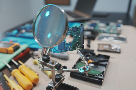 An overhead, detailed view of computer components spread out on a workspace, featuring an open hard drive casing and a green motherboard with an empty CPU socket ready for a processor.